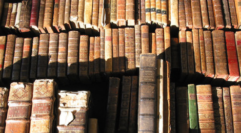 Several volumes of dusty, old books on a shelf.