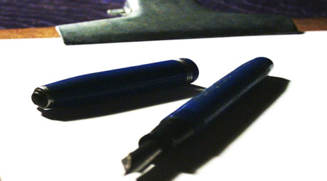 Close-up image of a fountain pen laying on a blank piece of paper on a clipboard.