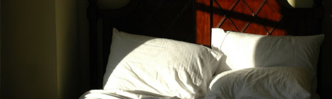 An empty bed, with the sunlight streaming in from unseen windows.