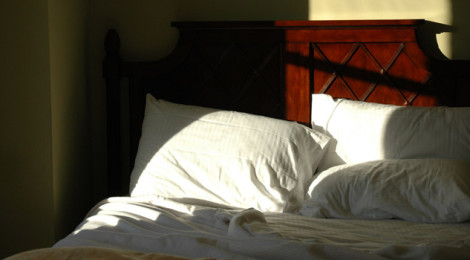 An empty bed, with the sunlight streaming in from unseen windows.